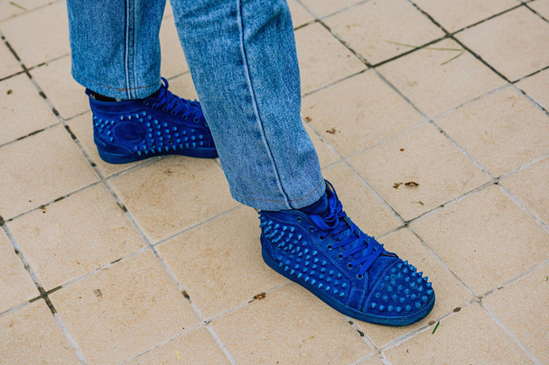 A man in blue sneakers with spikes. Walk around Tashkent city. Shoes with sharp rivets. - Fotó, kép