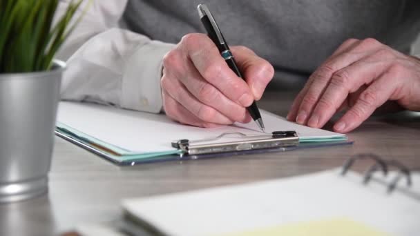 Businessman taking notes on clipboard, close-up - Footage, Video