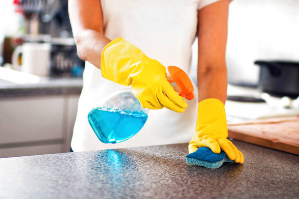 Vrouw met behulp van spray Polish aan keuken oppervlak schoon - Foto, afbeelding