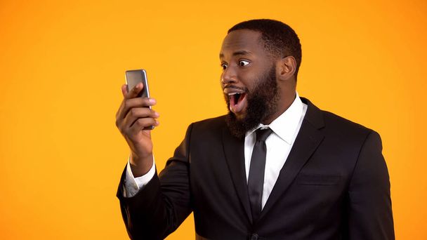 Surprised afro-american man receiving good news, mobile financial app, promotion - Foto, afbeelding