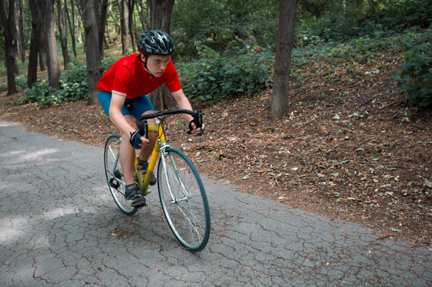 Ένας ποδηλάτης βόλτες με ποδήλατο δρόμου στο δρόμο στο δάσος. - Φωτογραφία, εικόνα
