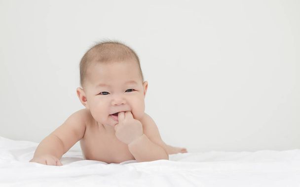 口の中で彼の指で右側を見てお風呂の後にリラックス小さなアジアの赤ちゃんの赤ちゃんの肖像画 - 写真・画像