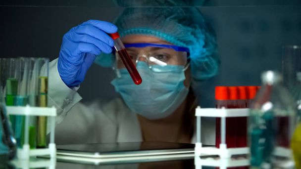 Laboratory technician with tablet PC analyzing blood serum in test tube - Фото, зображення