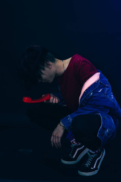 Young man with pink and black hair in red shirt on a dark blue background. - Fotó, kép