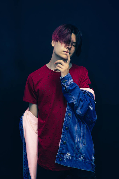 Young man with pink and black hair in red shirt on a dark blue background. - Photo, Image