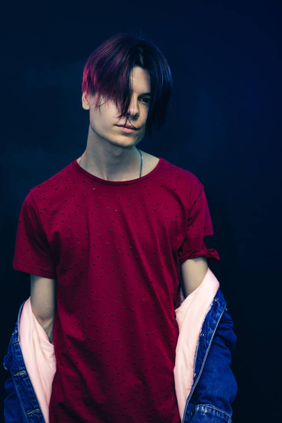 若いです男でピンクと黒の髪で赤いシャツで暗い青の背景. - 写真・画像