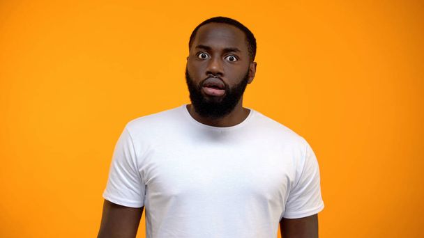 Shocked African-American man looking at camera isolated on yellow background - Фото, изображение