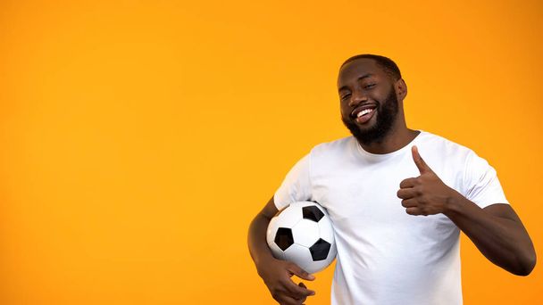 Attractive Afro-American man holding soccer ball and showing thumbs up sign - Foto, immagini