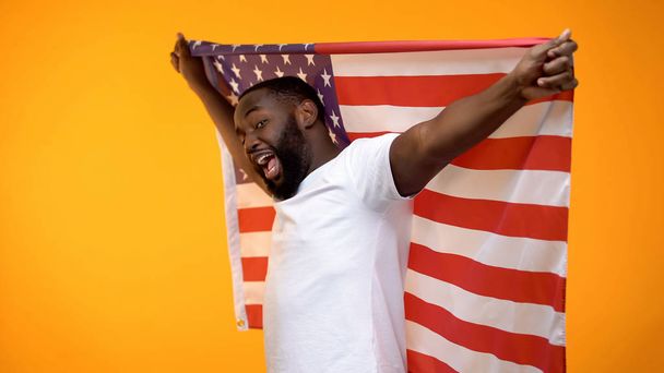 African-American man holding USA flag, supporting national sports team, fan - Фото, изображение