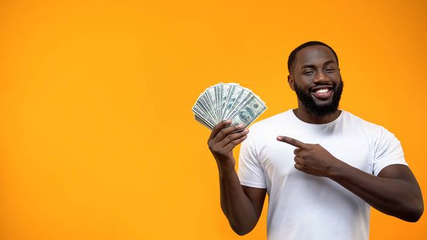 African-American man pointing finger into bunch of dollars, capital investment - Photo, image