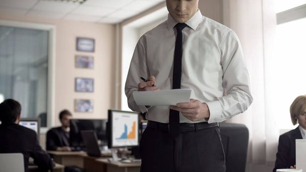 Male boss signing contract, employees working on background, busy lifestyle - 写真・画像