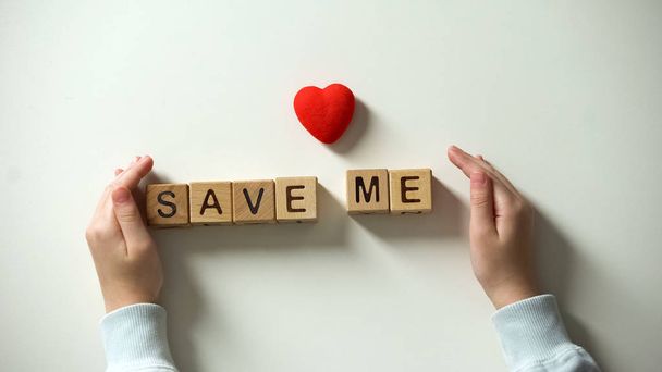 Childs hand putting heart sign and save me phrase made of wooden cubes, charity - Foto, Imagen