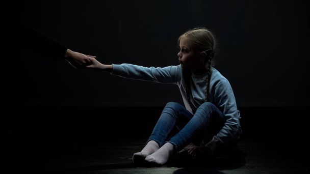 Little child in dark room accepting adult helping hand, social security concept - Foto, Imagem