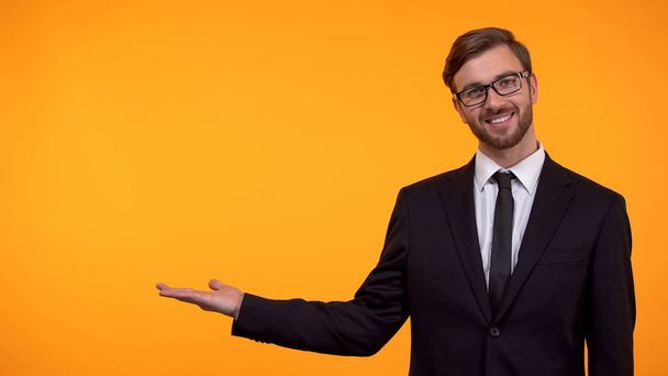 Lachende Business man wijzend handen op oranje achtergrond, plaats voor sjabloon - Foto, afbeelding
