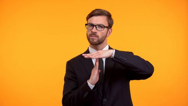 Business person showing time-out gesture, isolated on orange background deadline - Foto, imagen