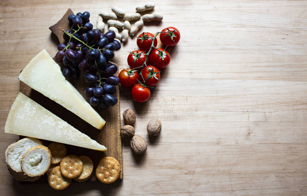 Τυρί σε ξύλινη σανίδα. Τυρί, σταφύλια και κράκερ. Χώρος αντιγραφής - Φωτογραφία, εικόνα