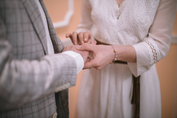 Пара молодоженов на свадебной церемонии носят обручальные кольца
 - Фото, изображение