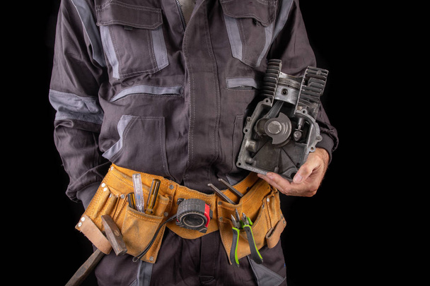 Mechanic with a small combustion engine in hand. A specialist in - Foto, Imagem