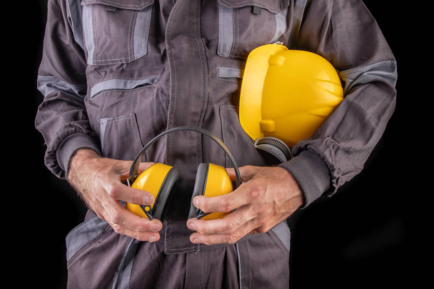 Виробничий працівник у робочому одязі з шоломом та захистом слуху
 - Фото, зображення
