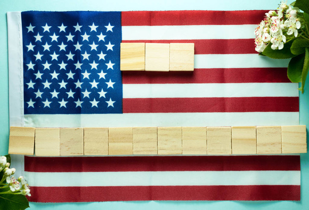 top view of empty blank for inscription on fifteen wooden cubes laid out on American flag on blue background - Foto, immagini