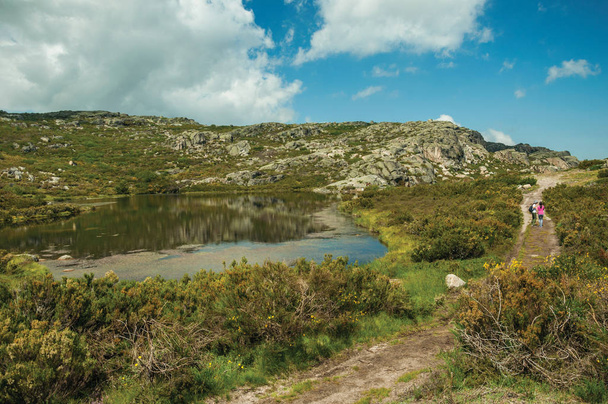 People on trail next to lake among rocky terrain - Fotografie, Obrázek