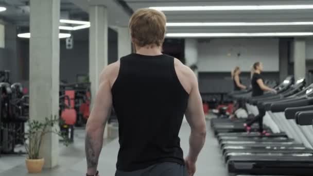 Redhead sport man walking modern gym. Bottom view. Follow-up shot of muscular man entering gym in slow motion. - Imágenes, Vídeo