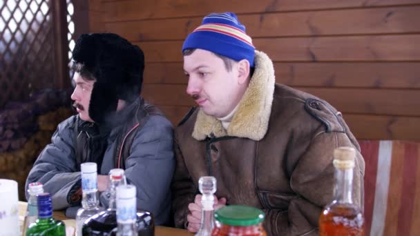 On winter day men sit and talk around table full of food and alcohol drink. - Footage, Video