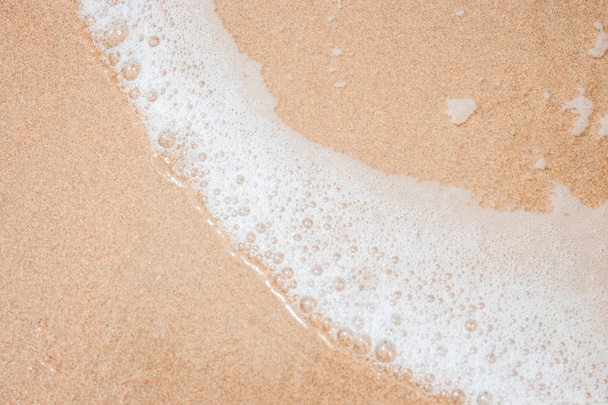 Espuma branca na areia da praia
 - Foto, Imagem