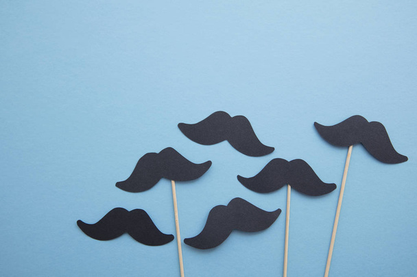 Black paper mustache on a blue background. Fathers day or mens health concept - Fotoğraf, Görsel
