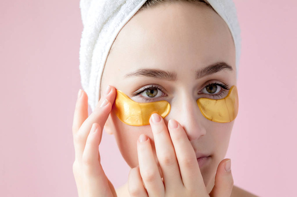 Portrait of Beauty Woman with Eye Patches on pink background. Woman Beauty Face with Mask under Eyes. Beautiful Female with natural Makeup and Gold Cosmetics Collagen Patches on Fresh Facial Skin - Fotó, kép