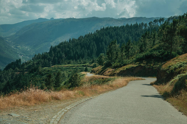 Carretera de campo que pasa a través del paisaje montañoso
 - Foto, Imagen