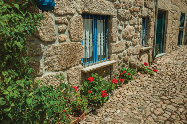 Фасад каменного дома с решетчатыми окнами и цветами
 - Фото, изображение