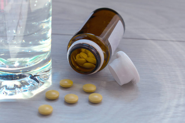 Vaso de agua y pastillas sobre la mesa
 - Foto, Imagen