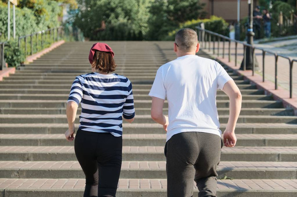 aktiver gesunder Lebensstil eines reifen Paares. Mann und Frau mittleren Alters laufen die Treppe hinauf, Blick von hinten - Foto, Bild