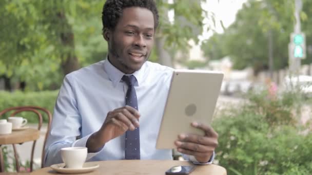 Online Video Chat on Tablet by African Businessman, Sitting in Outdoor Cafe - Filmagem, Vídeo