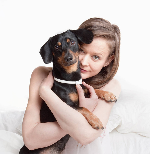 Жінка в ліжку тримає свого собаку
. - Фото, зображення