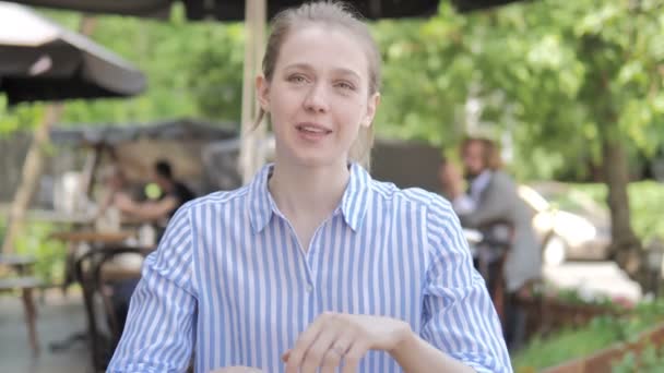 Bate-papo Video em linha pela mulher nova que senta-se no terraço do café - Filmagem, Vídeo