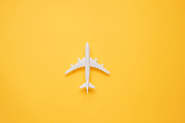 Flat lay design of travel concept with plane on yellow background with copy space. - Фото, изображение