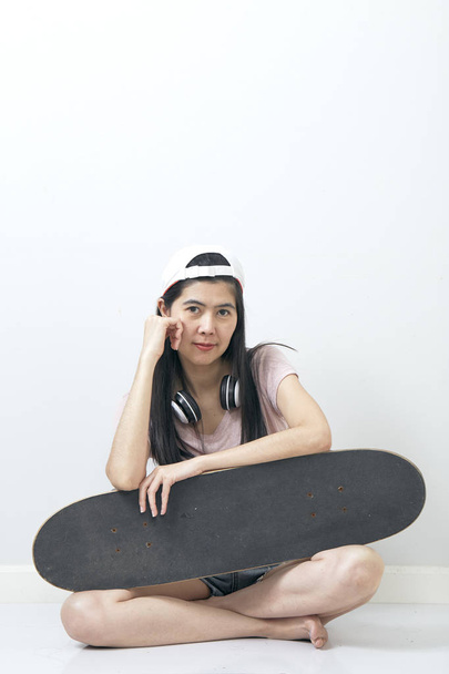 Hermosa chica asiática sosteniendo monopatín
 - Foto, imagen