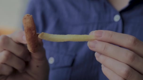 Dziewczyna wstawia kawałek smażone ziemniaki w pierścieniu cebuli. - Materiał filmowy, wideo