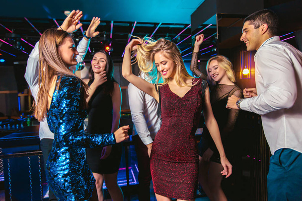 Young happy people are dancing in club. Nightlife and disco conc - Photo, Image