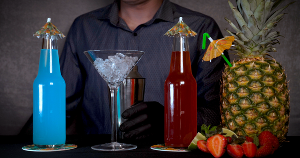 Der Barmann (Barkeeper) bereitet verschiedene Getränke (Cocktails) für eine Party zu. in der Bar in der Disco oder zu Hause, kalte Fruchtgetränke sind auf schwarzem Hintergrund zu sehen. - Filmmaterial, Video