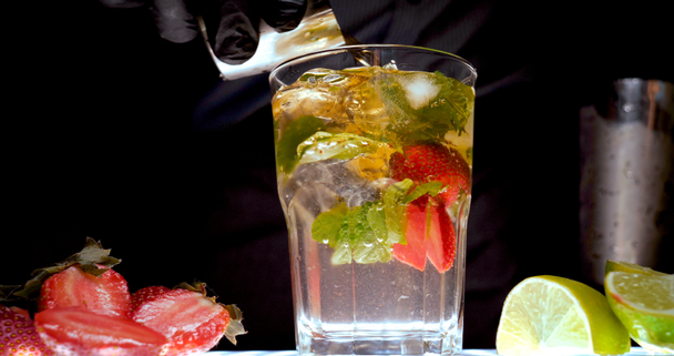 The Barman (bartender) prepares various drinks (cocktails) for a party. In the bar at the disco or at home, fruit cold drinks are seen on a black background. - Footage, Video