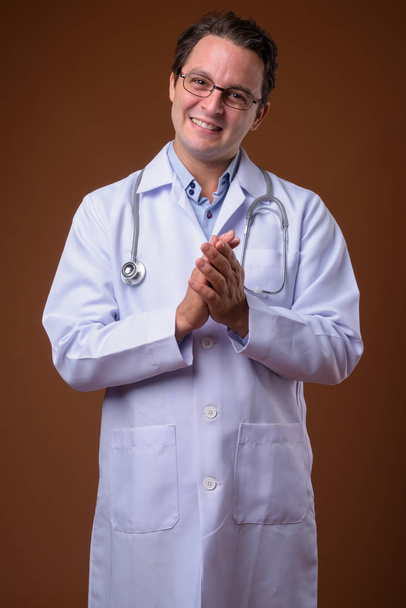 Studio shot of Italian man doctor against brown background - Photo, Image