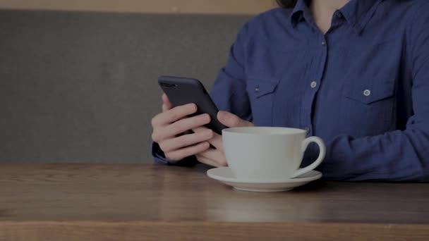 A beautiful girl is sitting in a cafe with a phone and drinking coffee. - Záběry, video