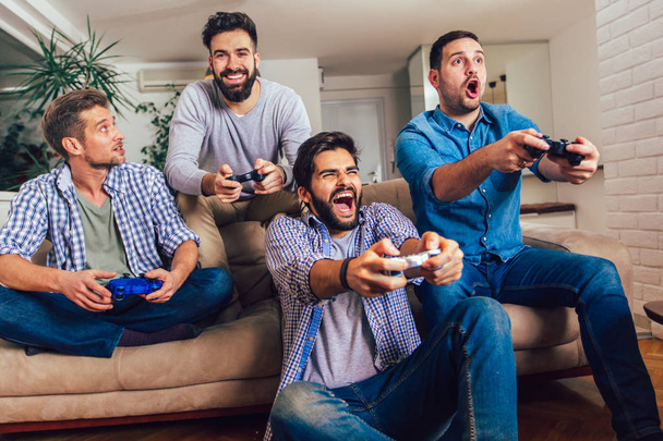 Mosolygó férfi barátok videojátékok otthon és szórakozás. - Fotó, kép