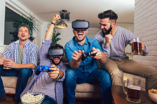 Happy friends playing video games with virtual reality glasses - - 写真・画像