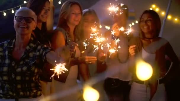 Uudenvuodenaattona juhla ryhmä sekaikäisiä ja sukupolvien naisten hauskaa sparklers ulkona - ihmiset hauskaa yhdessä ystävyys - pimeä ilta aikaa ja puolueen toimintaa - Materiaali, video