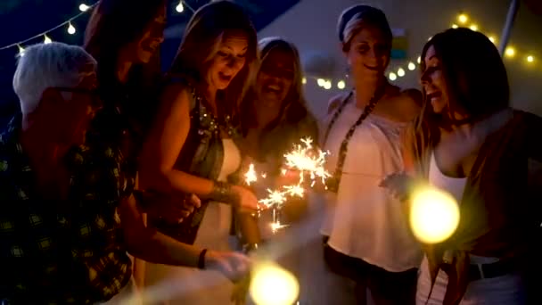 Празднование Нового года с группой смешанных возрастов и поколений женщин, веселящихся с бенгальскими огнями на открытом воздухе - люди, веселящиеся вместе в дружбе - темное вечернее время и активность на вечеринке - Кадры, видео