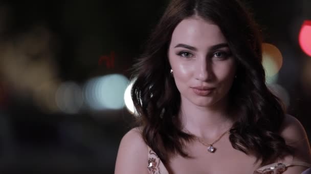 Beautiful attractive woman looking at camera in night city, slow motion - Záběry, video